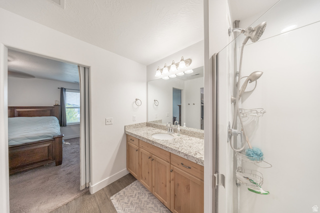 4765 Breezy Patch Road Eagle Mountain, UT 84005 - Photo 17 of 25 Bathroom vanity featuring a light-toned wood-finish cabinet with chrome hardware, an integrated sink, and a speckled countertop