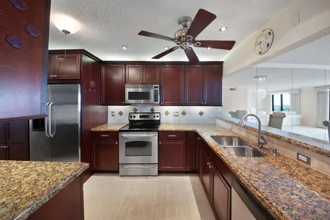 a kitchen with stainless steel appliances granite countertop wooden cabinets stove top oven and sink