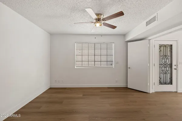 an empty room with wooden floor fan and windows