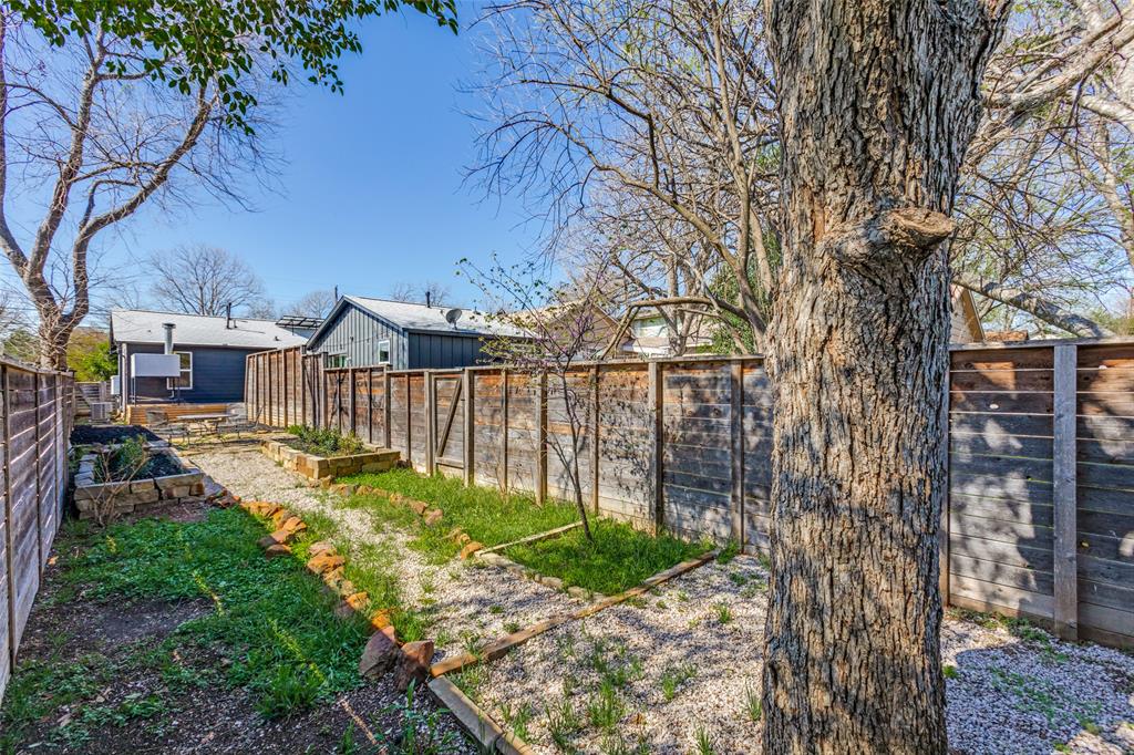2012 Payne Avenue, Unit A Austin, TX 78757 - Photo 31 of 33 Private backyard featuring a large mature tree, gravel pathways, and established planter beds
