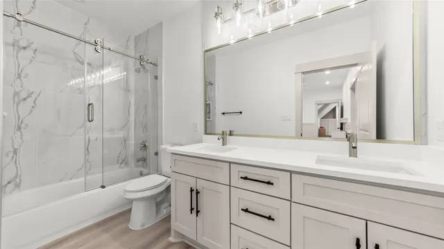 a bathroom with a double vanity sink toilet mirror and shower