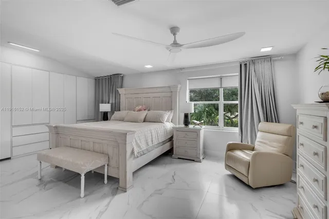 a bedroom with a large bed and a flat tv screen on dresser