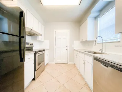 a kitchen with granite countertop a sink stove and cabinets