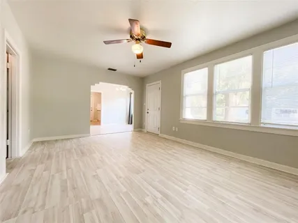 a view of an empty room with a window and wooden floor