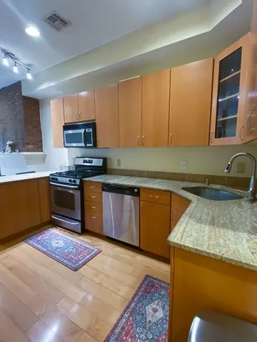 a kitchen with stainless steel appliances granite countertop wooden cabinets a stove top oven a sink and dishwasher