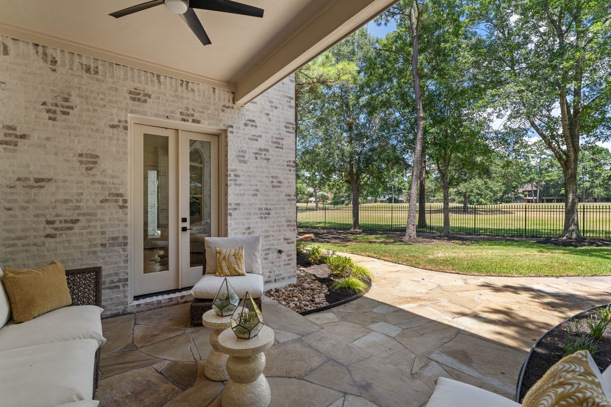 31 Hollymead Drive Spring, TX 77381 - Photo 20 of 50 This inviting covered patio off the family room features a cozy seating area set against a backdrop of charming light brick. Overlooking a lush, tree-lined yard with a view of open green space and the Tee Box for Hole #3 of the King golf course, it's perfect for relaxation and entertaining.