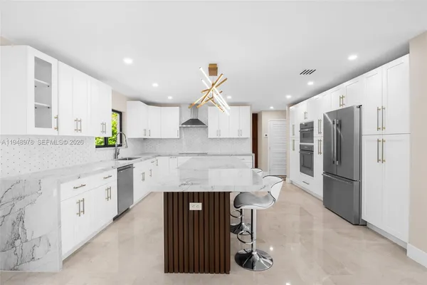 a kitchen with stainless steel appliances kitchen island granite countertop a refrigerator and a stove top oven
