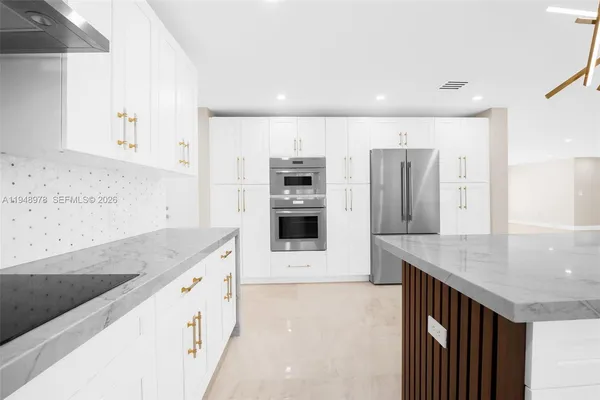 a kitchen with stainless steel appliances kitchen island granite countertop a refrigerator and a stove top oven