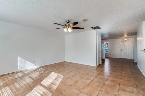 a view of an empty room with chandelier fan