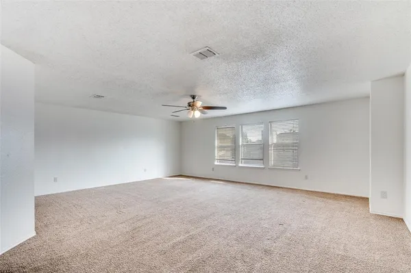 an empty room with windows and ceiling fan