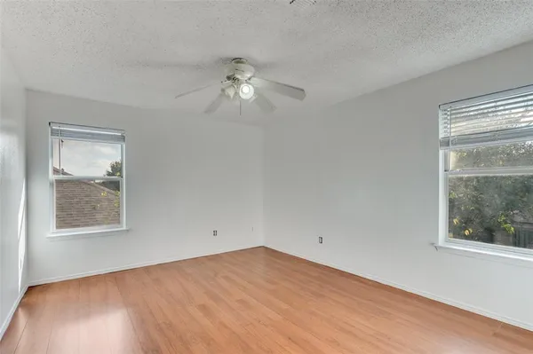 a view of empty room with wooden floor and fan