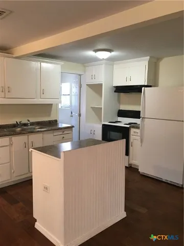 a kitchen with stainless steel appliances a refrigerator a stove a sink and white cabinets