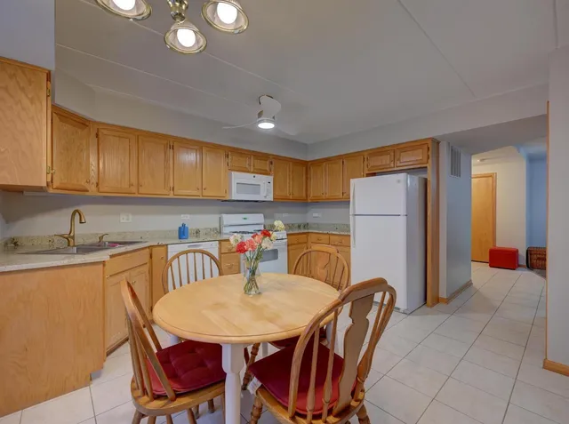 a kitchen with stainless steel appliances granite countertop a sink a stove a dining table and chairs