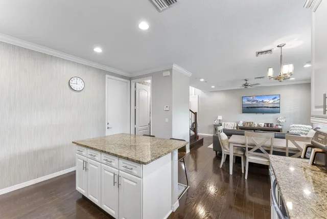 a open kitchen with granite countertop a stove a sink a dining table and chairs with wooden floor