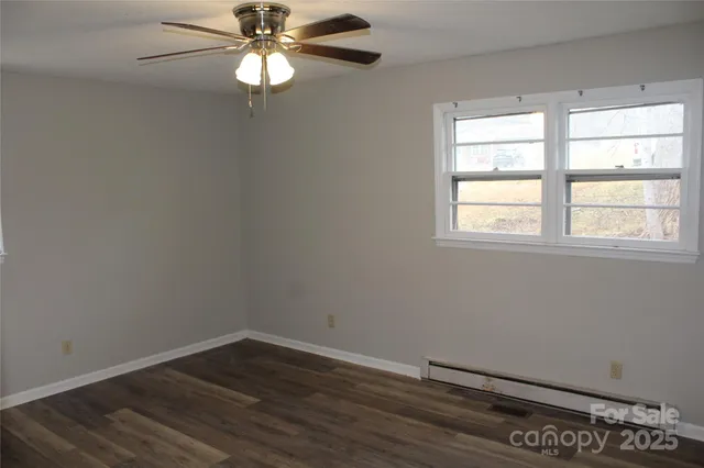 an empty room with wooden floor chandelier fan and windows