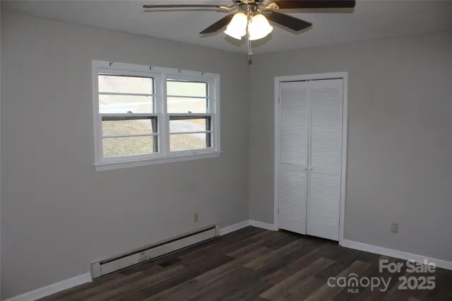 an empty room with wooden floor fan and windows