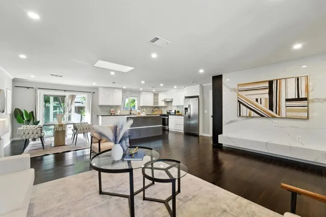 a living room with couches chairs and kitchen view with wooden floor