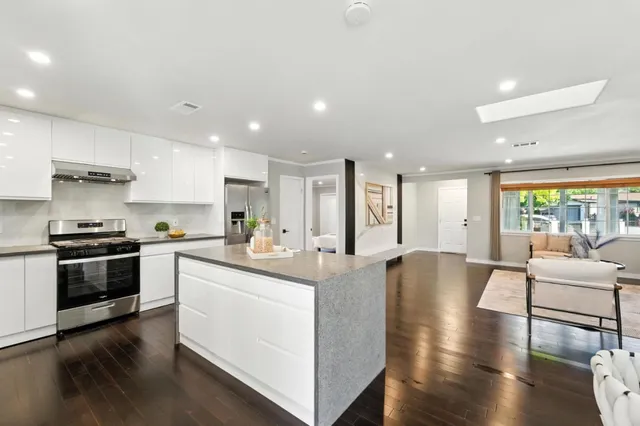 a large kitchen with stainless steel appliances granite countertop a stove and a large window
