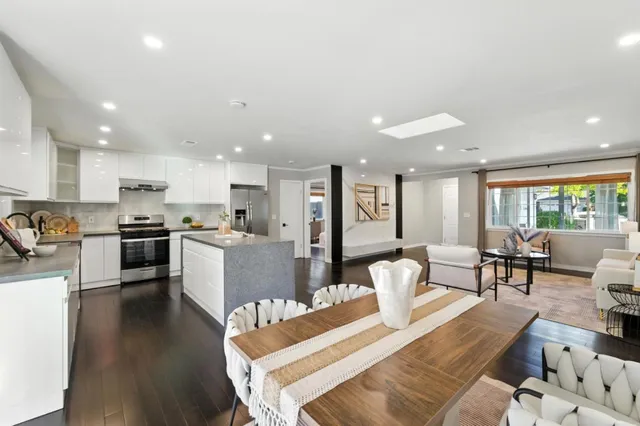 a living room with couches and kitchen view with wooden floor