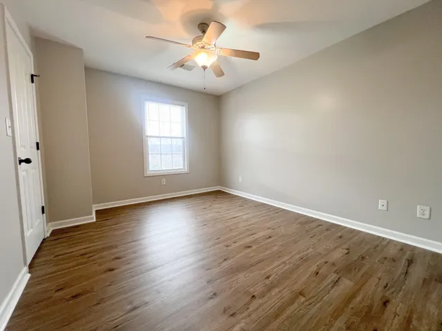an empty room with wooden floor and windows