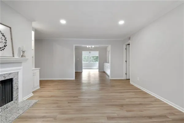 a view of an empty room with wooden floor and a fireplace