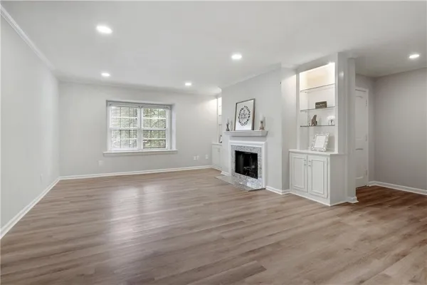 an empty room with wooden floor and a kitchen