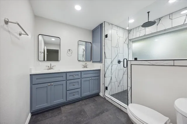 a bathroom with a toilet sink double mirror and shower