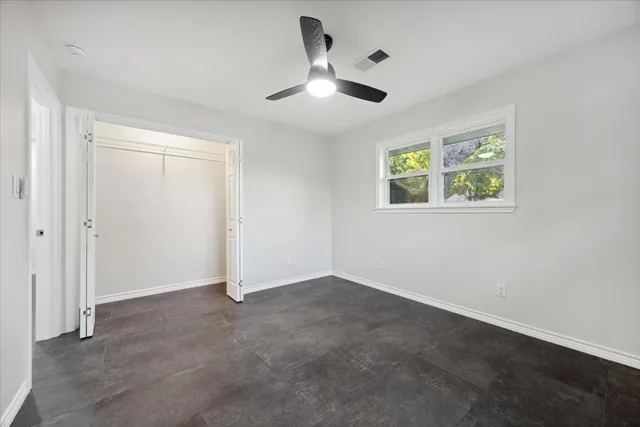 an empty room with windows and ceiling fan