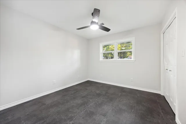 an empty room with a chandelier fan and windows