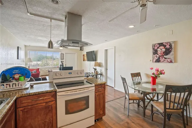 a kitchen with stainless steel appliances granite countertop a dining table chairs stove and white cabinets