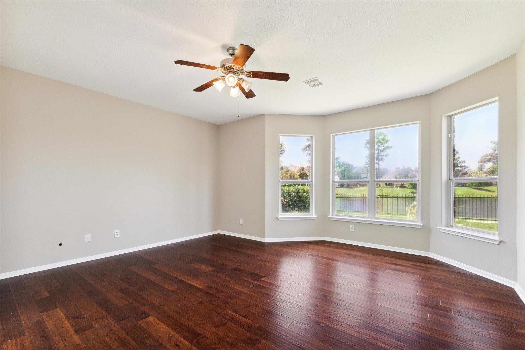 30507 Russell Point Drive Spring, TX 77386 - Photo 14 of 33 Bright and spacious primary bedroom with hardwood floors and large windows offering a scenic water view and lush backyard.