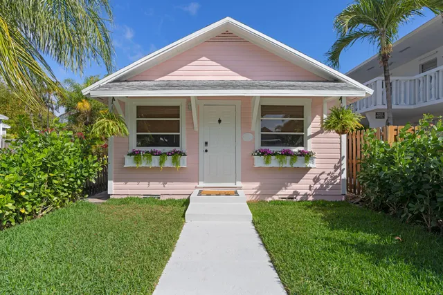 a front view of a house with a yard and potted plants