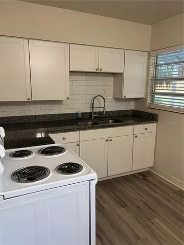 a kitchen with granite countertop a sink a stove and cabinets
