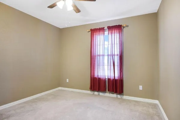 an empty room with a chandelier fan and a ceiling fan