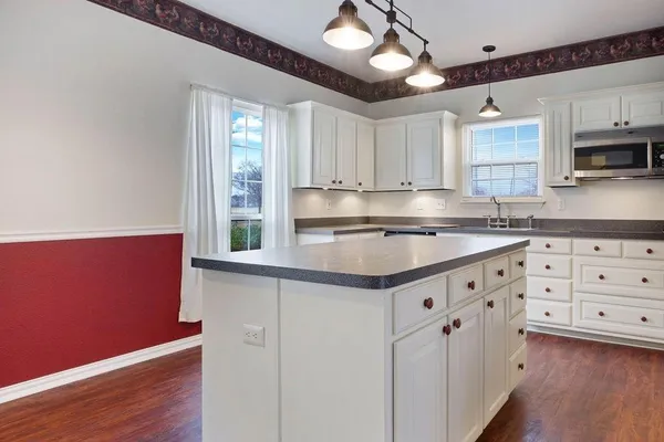 a kitchen with granite countertop a sink cabinets and wooden floor