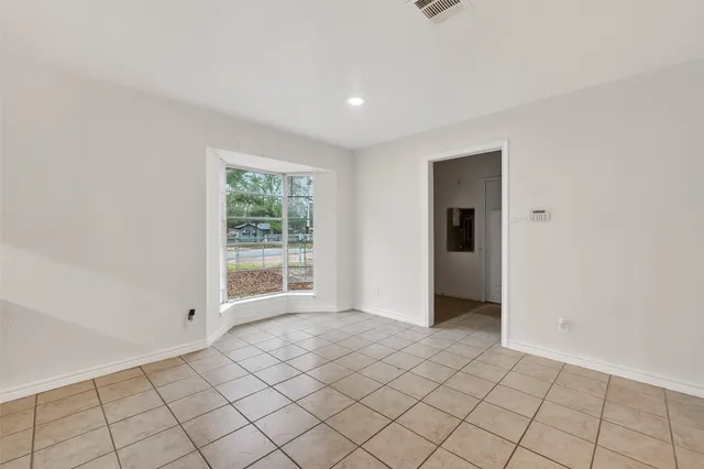 an empty room with kitchen view and a fireplace
