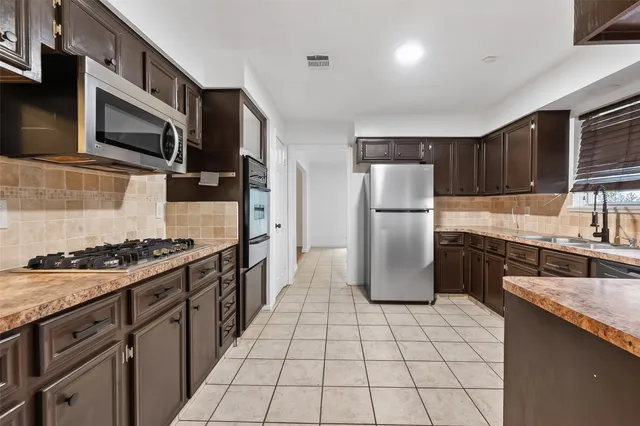 a kitchen with stainless steel appliances a sink stove and cabinets