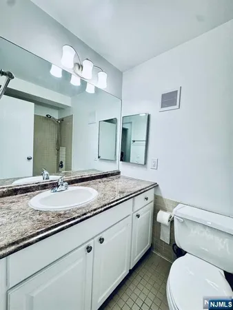 a bathroom with a granite countertop toilet sink and mirror