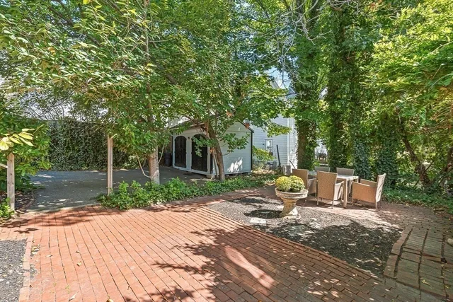 a view of a patio with table and chairs with wooden fence and large trees