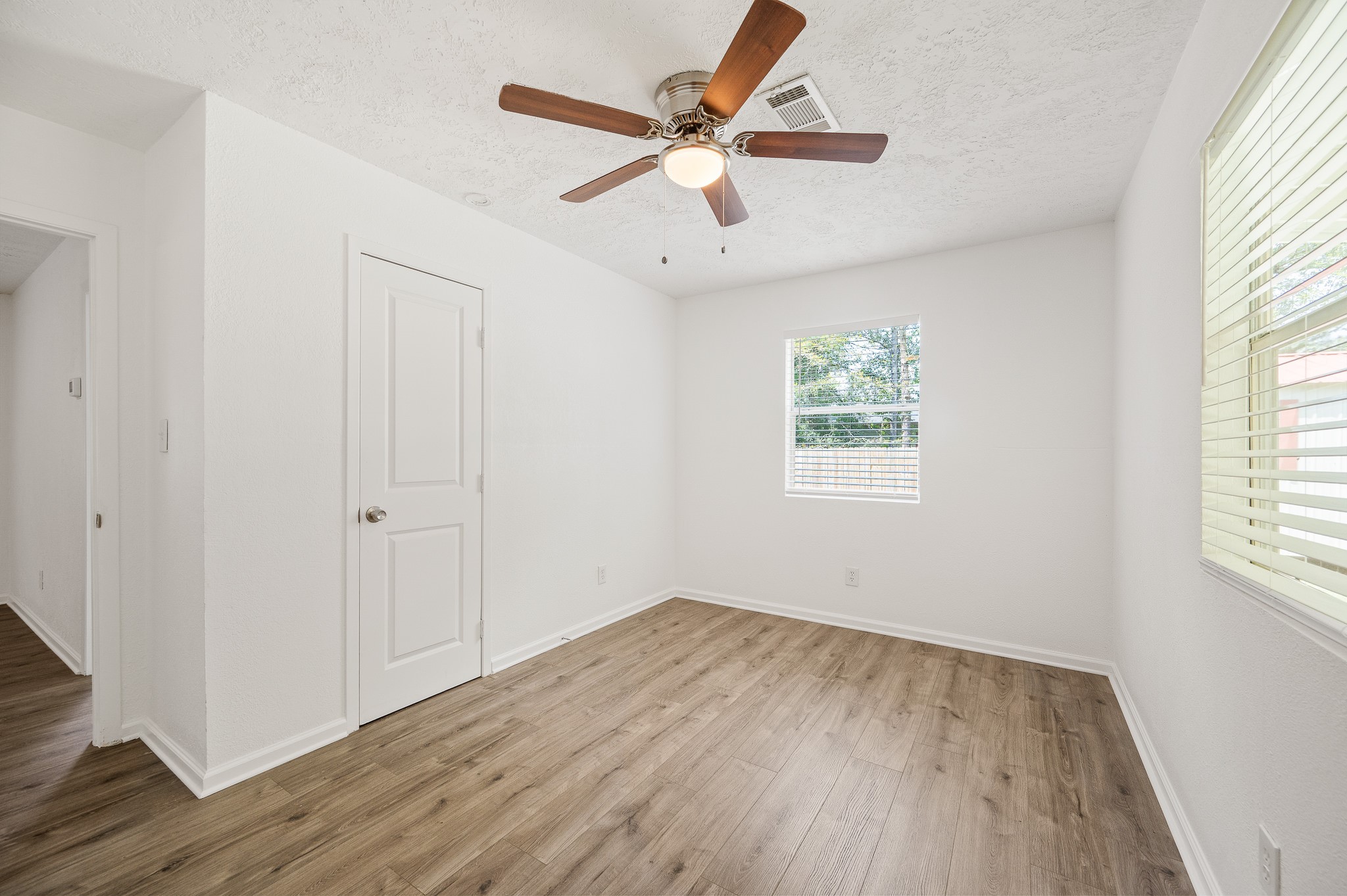 61 Hicks Loop West Cleveland, TX 77328 - Photo 20 of 38 Bright and airy room featuring sleek wood flooring, a modern ceiling fan, and ample natural light streaming through large windows.