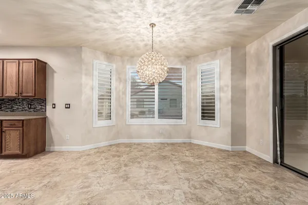an empty room with a chandelier fan and windows