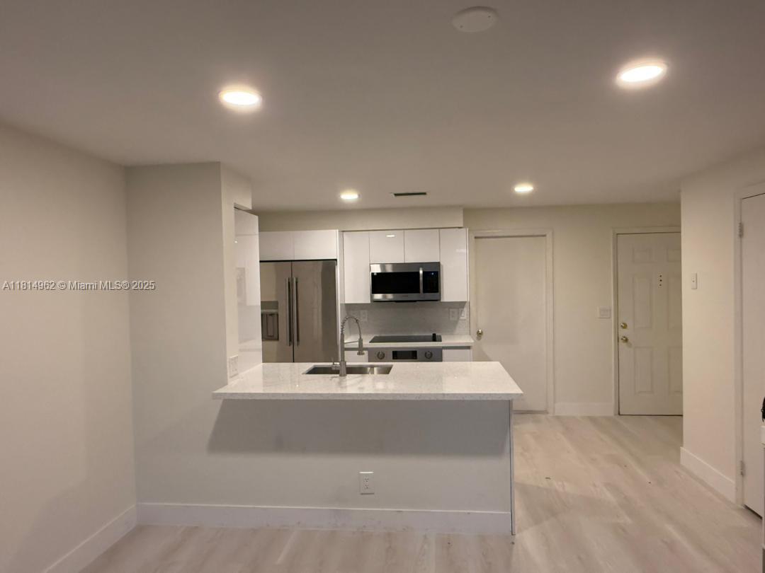 790 Sorrento Drive, Unit 790 Weston, FL 33326 - Photo 2 of 5 a room with a microwave a sink and cabinets