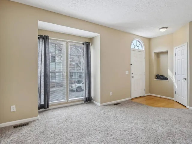 a view of an empty room with window and closet area