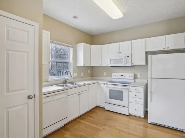a kitchen with white cabinets sink and white appliances