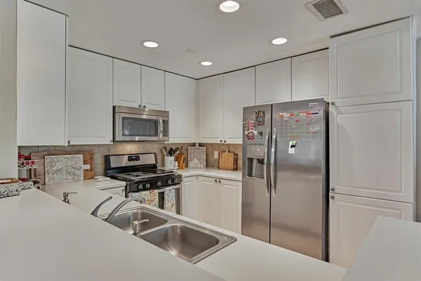 a kitchen with stainless steel appliances a refrigerator sink and microwave