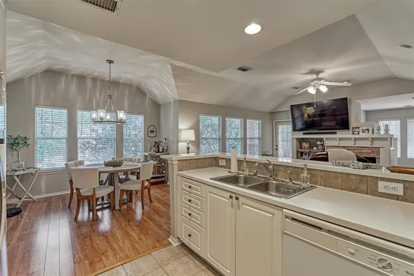 a open kitchen with stainless steel appliances granite countertop a sink dishwasher a stove and a dining table with wooden floor