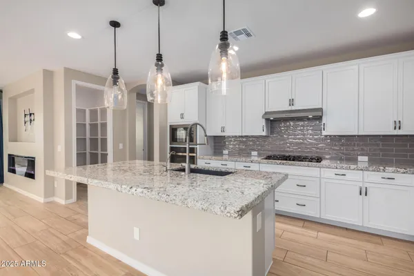 a kitchen with stainless steel appliances granite countertop a sink a stove and a wooden floors