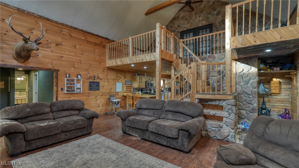 8498 Euga Road Newcomerstown, OH 43832 - Photo 5 of 49 Living room with a ceiling fan, high vaulted ceiling, stairway, wood-type flooring, and wooden walls