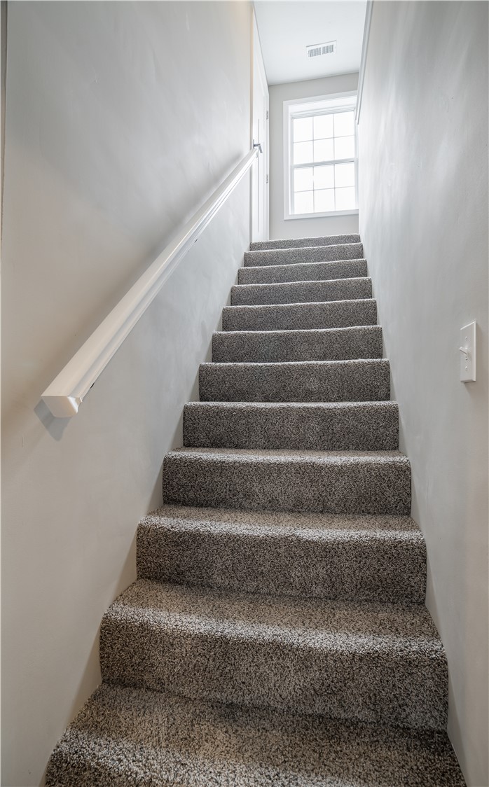 8240 Looney Road Piqua, OH 45356 - Photo 22 of 49 This interior staircase features carpet flooring, a classic window, and a door, creating a practical and inviting transition.