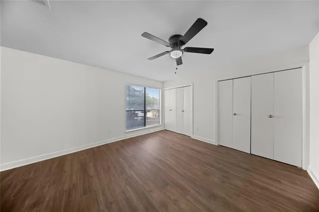a view of empty room with wooden floor and ceiling fan